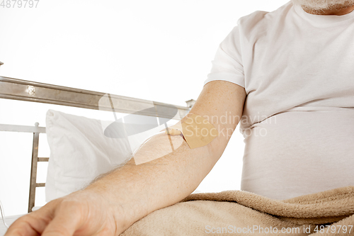 Image of Elderly old man recovering in a hospital bed isolated on white