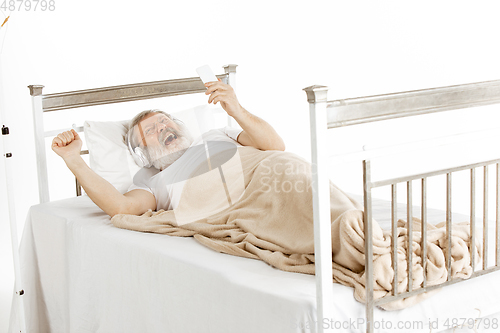 Image of Elderly old man recovering in a hospital bed isolated on white