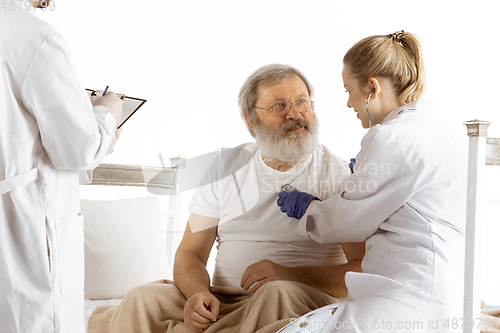 Image of Elderly old man recovering in a hospital bed isolated on white