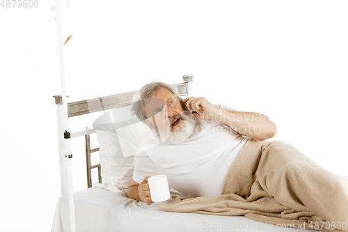 Image of Elderly old man recovering in a hospital bed isolated on white