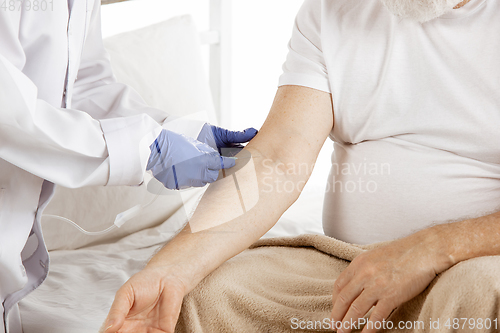 Image of Elderly old man recovering in a hospital bed isolated on white