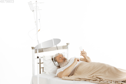 Image of Elderly old man recovering in a hospital bed isolated on white