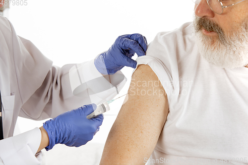 Image of Elderly old man recovering in a hospital bed isolated on white