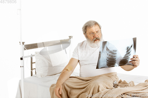 Image of Elderly old man recovering in a hospital bed isolated on white