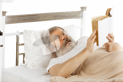 Image of Elderly old man recovering in a hospital bed isolated on white