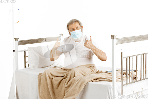 Image of Elderly old man recovering in a hospital bed isolated on white