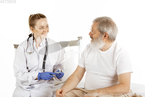 Image of Elderly old man recovering in a hospital bed isolated on white