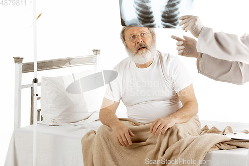 Image of Elderly old man recovering in a hospital bed isolated on white