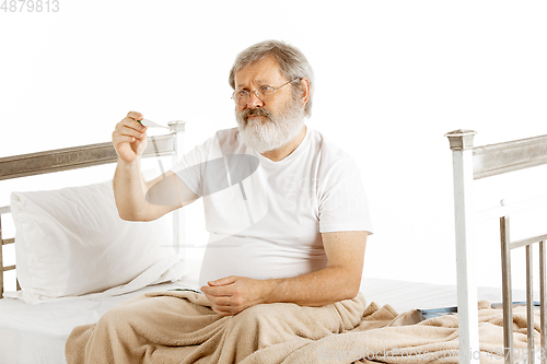 Image of Elderly old man recovering in a hospital bed isolated on white