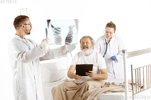 Image of Elderly old man recovering in a hospital bed isolated on white