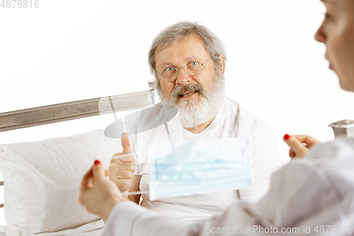 Image of Elderly old man recovering in a hospital bed isolated on white