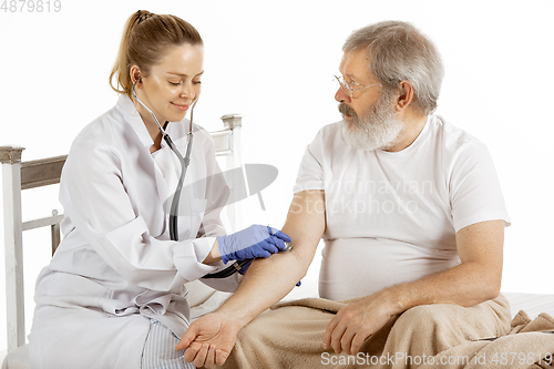 Image of Elderly old man recovering in a hospital bed isolated on white