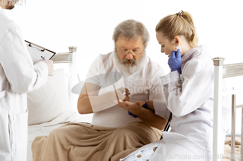 Image of Elderly old man recovering in a hospital bed isolated on white