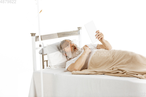 Image of Elderly old man recovering in a hospital bed isolated on white