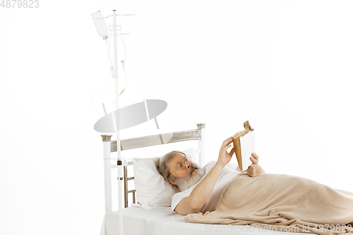 Image of Elderly old man recovering in a hospital bed isolated on white