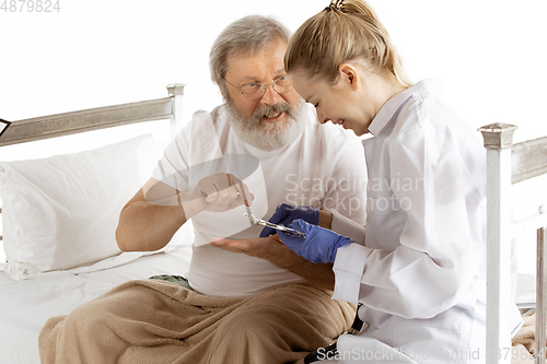 Image of Elderly old man recovering in a hospital bed isolated on white