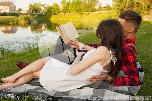 Image of Caucasian young and happy couple enjoying a picnic in the park on summer day