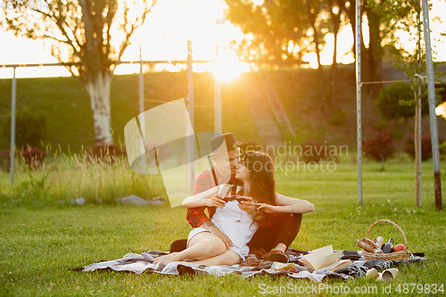 Image of Caucasian young and happy couple enjoying a picnic in the park on summer day