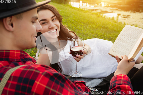 Image of Caucasian young and happy couple enjoying a picnic in the park on summer day