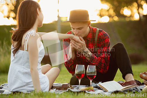 Image of Caucasian young and happy couple enjoying a picnic in the park on summer day