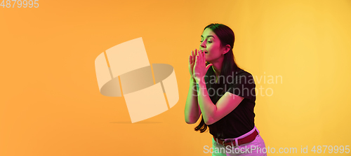 Image of Caucasian young woman\'s portrait on yellow background in neon light