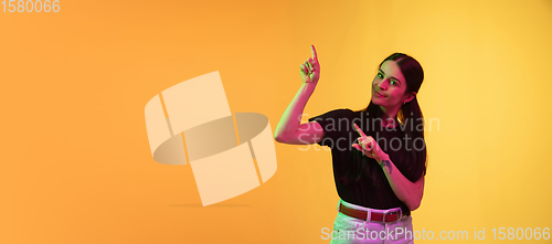Image of Caucasian young woman\'s portrait on yellow background in neon light