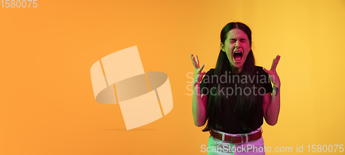 Image of Caucasian young woman\'s portrait on yellow background in neon light