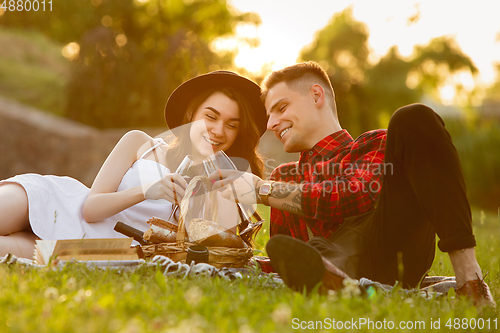 Image of Caucasian young and happy couple enjoying a picnic in the park on summer day