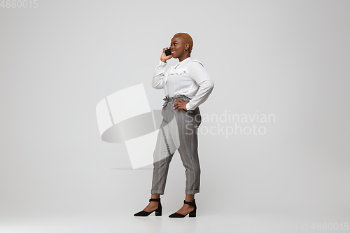 Image of Young african-american woman in office attire on gray background. Bodypositive female character. plus size businesswoman