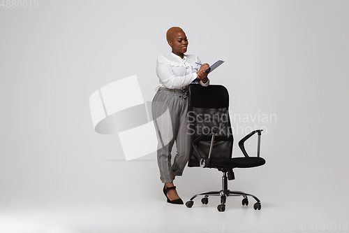 Image of Young african-american woman in office attire on gray background. Bodypositive female character. plus size businesswoman