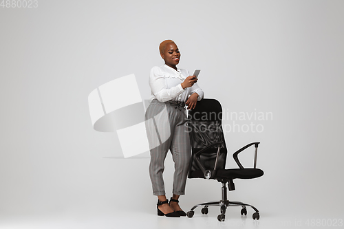 Image of Young african-american woman in office attire on gray background. Bodypositive female character. plus size businesswoman