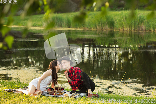 Image of Caucasian young and happy couple enjoying a picnic in the park on summer day