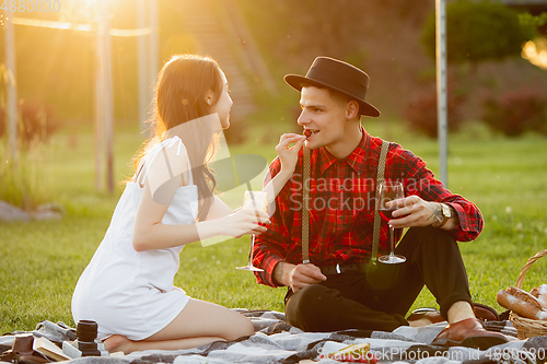 Image of Caucasian young and happy couple enjoying a picnic in the park on summer day