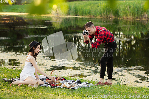 Image of Caucasian young and happy couple enjoying a picnic in the park on summer day