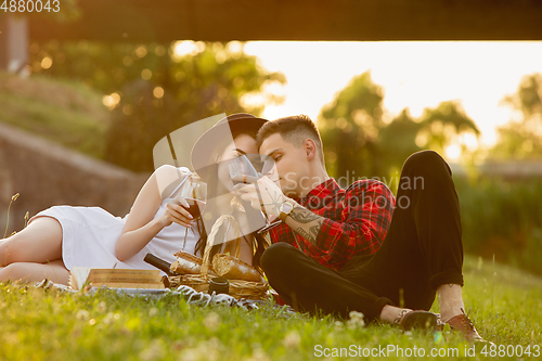 Image of Caucasian young and happy couple enjoying a picnic in the park on summer day