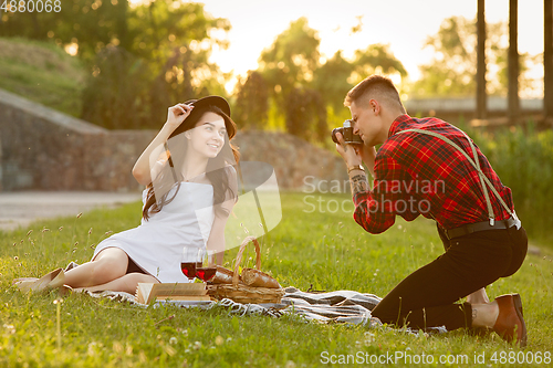 Image of Caucasian young and happy couple enjoying a picnic in the park on summer day