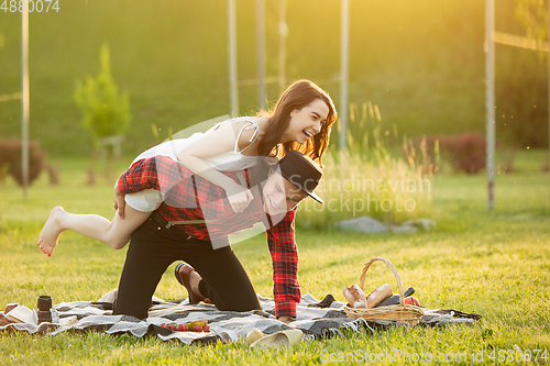 Image of Caucasian young and happy couple enjoying a picnic in the park on summer day