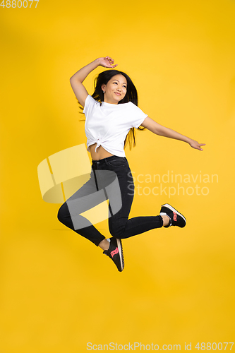Image of Portrait of young asian woman isolated on yellow studio background
