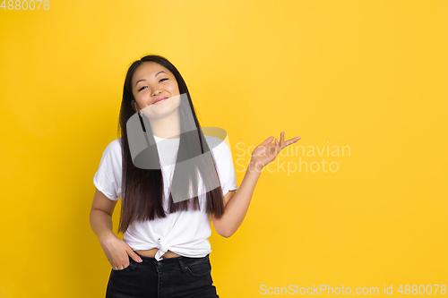 Image of Portrait of young asian woman isolated on yellow studio background