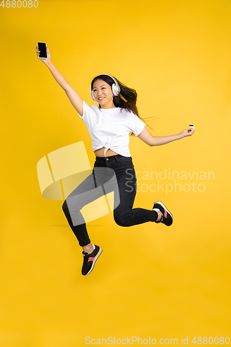 Image of Portrait of young asian woman isolated on yellow studio background