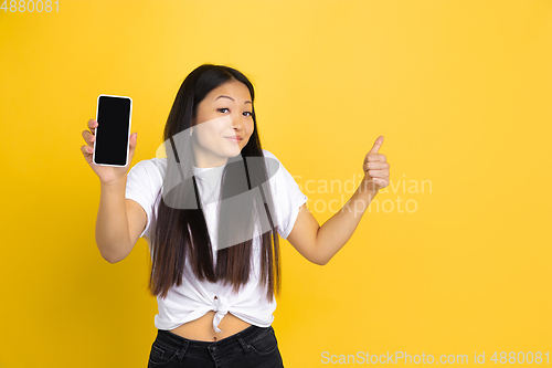 Image of Portrait of young asian woman isolated on yellow studio background