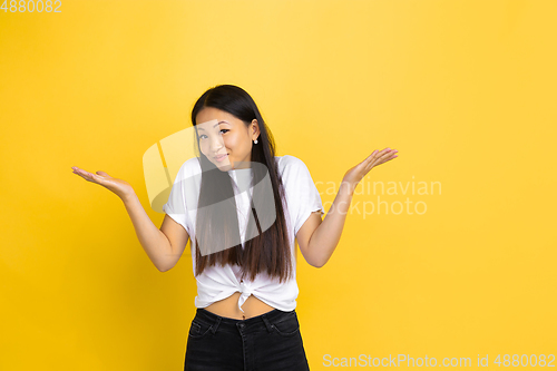 Image of Portrait of young asian woman isolated on yellow studio background