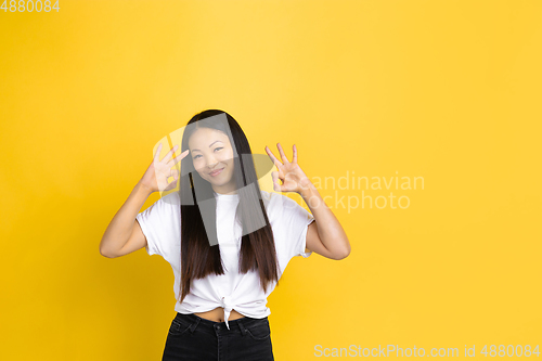 Image of Portrait of young asian woman isolated on yellow studio background