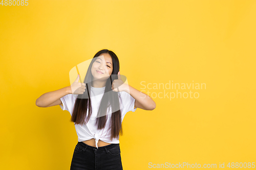 Image of Portrait of young asian woman isolated on yellow studio background