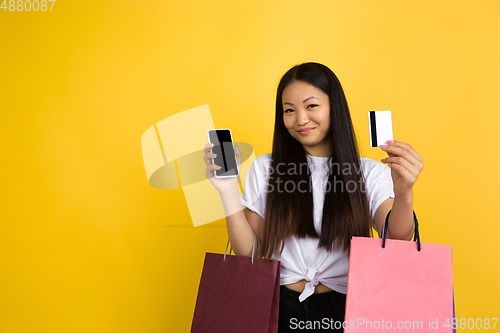 Image of Portrait of young asian woman isolated on yellow studio background