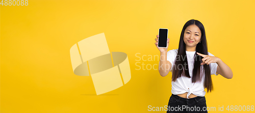 Image of Portrait of young asian woman isolated on yellow studio background
