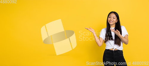 Image of Portrait of young asian woman isolated on yellow studio background