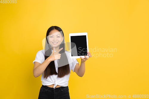 Image of Portrait of young asian woman isolated on yellow studio background