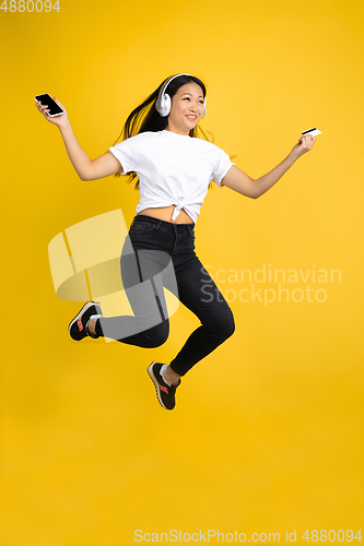 Image of Portrait of young asian woman isolated on yellow studio background