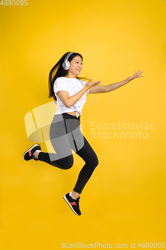 Image of Portrait of young asian woman isolated on yellow studio background